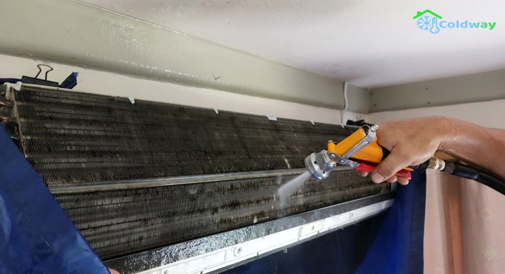 A technician performing an aircon chemical wash on the internal unit