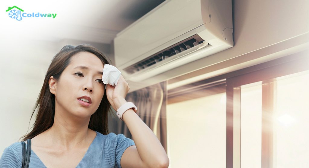 A woman wiping her sweat in front of the air conditioner